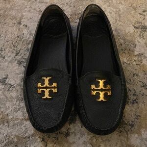 Tory Burch black leather loafers with a gold emblem.